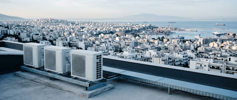 Κλιματιστικές μονάδες σε ταράτσα με θέα τις ταράτσες της Αθήνας ως το λιμάνι του Πειραιά